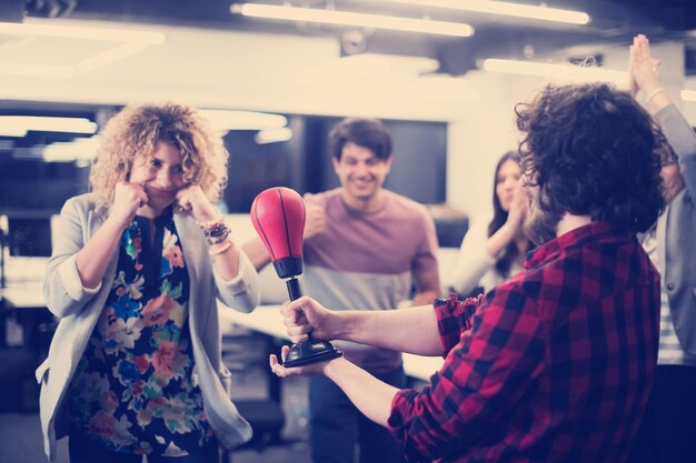 Foto equipo de negocios de inicio multiétnico de desarrolladores de software divirtiéndose mientras boxean en la oficina, empleados diversos emocionados riendo disfrutando de actividades divertidas en el descanso del trabajo, trabajadores creativos y amigables jugando