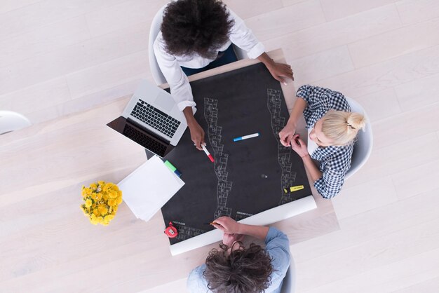 Equipo de negocios de inicio multiétnico en reunión en interior de oficina moderna y brillante lluvia de ideas, vista superior