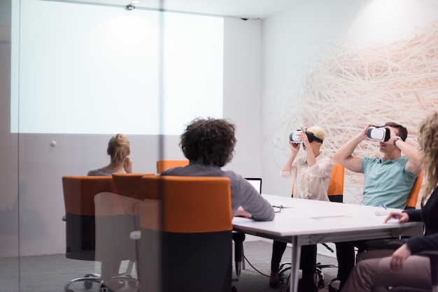 El equipo de negocios de inicio que usa auriculares de realidad virtual en una reunión nocturna en la oficina Reunión de desarrolladores con un simulador de realidad virtual alrededor de una mesa en una oficina creativa.