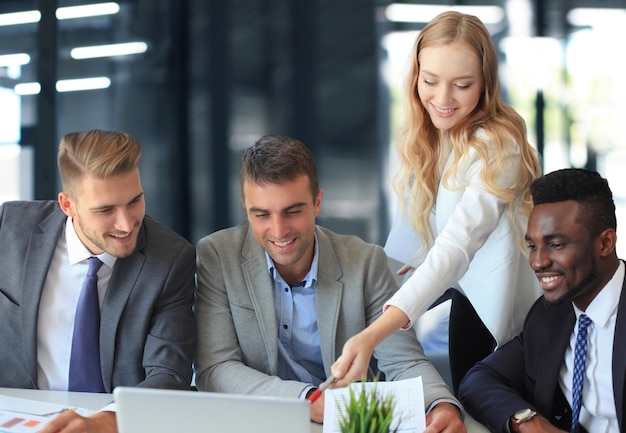 Equipo de negocios de inicio en la reunión en el interior de la oficina moderna y luminosa lluvia de ideas trabajando en una computadora portátil y una tableta