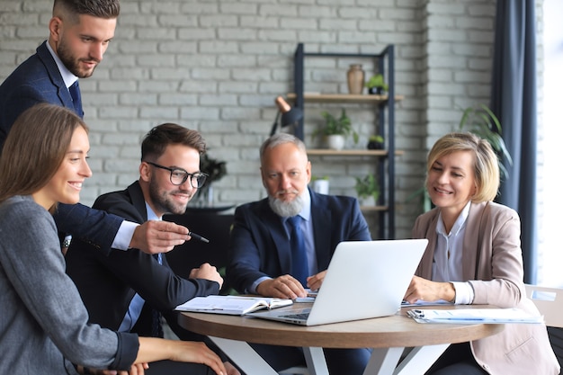 Equipo de negocios de inicio en reunión en el interior de la oficina moderna y luminosa y trabajando en equipo portátil.