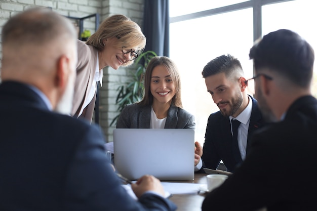 Equipo de negocios de inicio en reunión en el interior de la oficina moderna y luminosa y trabajando en equipo portátil.