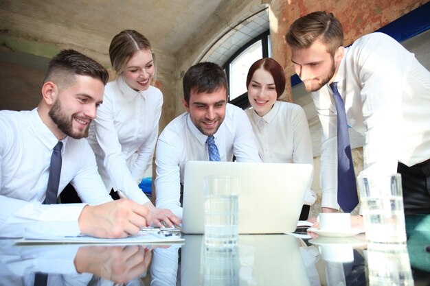 Foto equipo de negocios de inicio en reunión en el interior de la oficina moderna y luminosa y trabajando en equipo portátil.