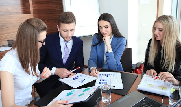 Equipo de negocios de inicio en reunión en la lluvia de ideas interior de la oficina moderna y luminosa, trabajando en una computadora portátil y tableta