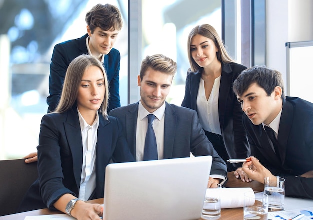 equipo de negocios de inicio en la reunión en la lluvia de ideas interior de la oficina moderna y luminosa, trabajando en la computadora portátil y la tableta.