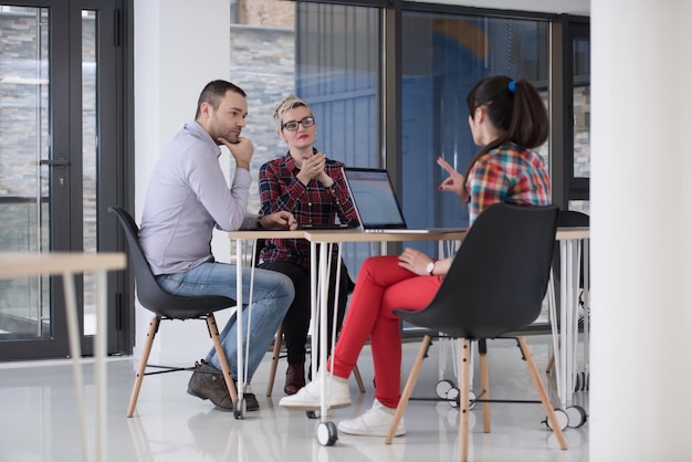 Equipo de negocios de inicio en reunión en la lluvia de ideas interior de la oficina moderna y luminosa, trabajando en una computadora portátil y tableta