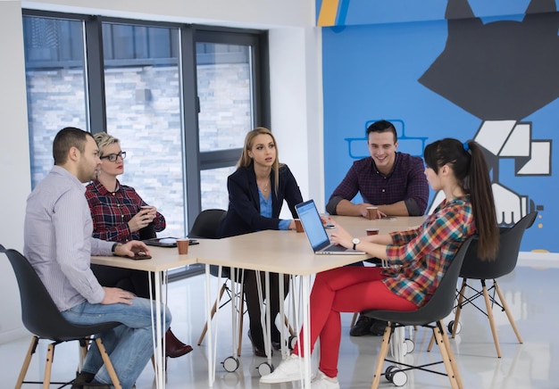 Equipo de negocios de inicio en reunión en la lluvia de ideas interior de la oficina moderna y luminosa, trabajando en una computadora portátil y tableta