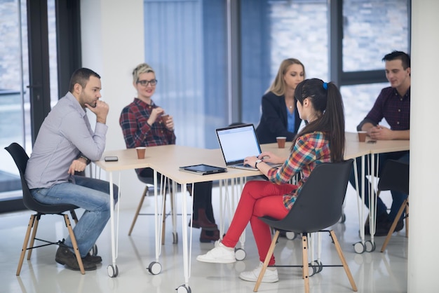 Equipo de negocios de inicio en reunión en la lluvia de ideas interior de la oficina moderna y luminosa, trabajando en una computadora portátil y tableta