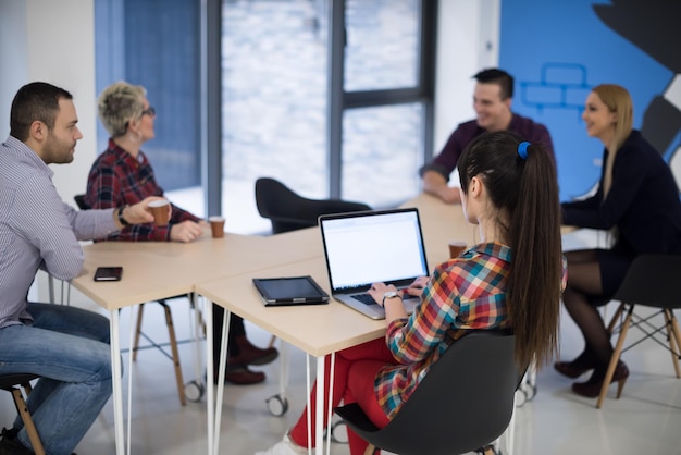 Equipo de negocios de inicio en reunión en la lluvia de ideas interior de la oficina moderna y luminosa, trabajando en una computadora portátil y tableta