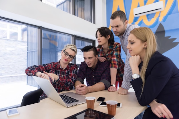 Equipo de negocios de inicio en reunión en la lluvia de ideas interior de la oficina moderna y luminosa, trabajando en una computadora portátil y tableta