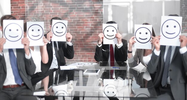 Foto el equipo de negocios mantiene íconos sonrientes sentados en el escritorio