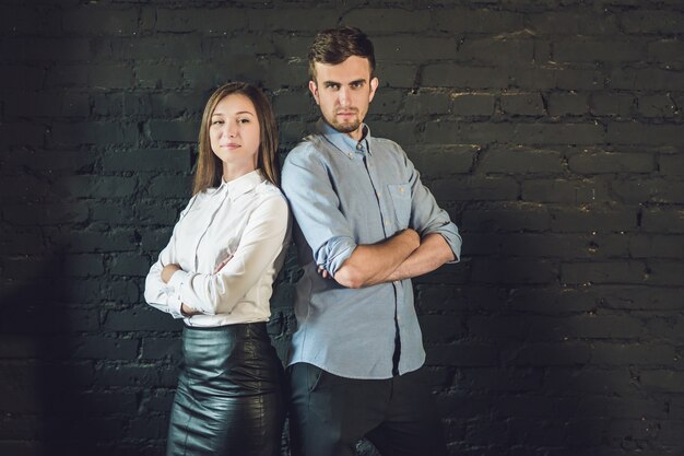 Equipo de negocios masculino y femenino formado por jóvenes empresarios de pie sobre una superficie oscura.