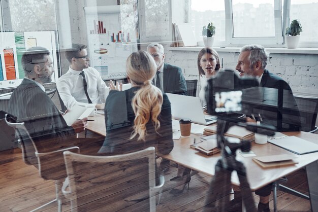 Equipo de negocios moderno discutiendo la estrategia mientras filma la reunión del personal en la sala de juntas