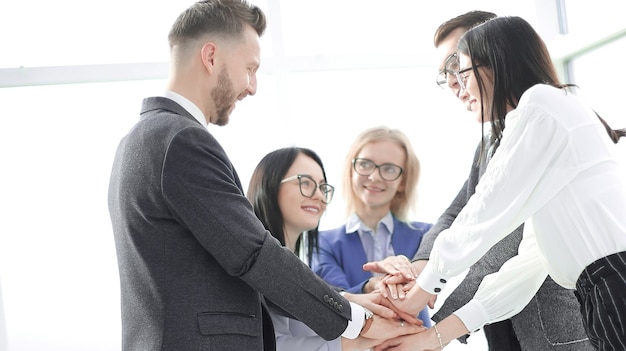 Foto equipo de negocios mostrando su unidad mientras está de pie en la oficina. el concepto de trabajo en equipo