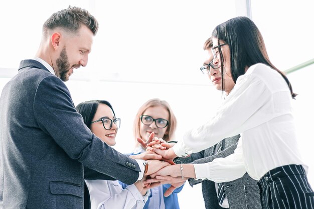 Foto equipo de negocios mostrando su unidad mientras está de pie en la oficina. el concepto de trabajo en equipo