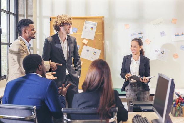 Equipo de negocios multiétnico, varios trabajadores de oficina conversando y sonriendo mientras mantienen una reunión con colegas en una oficina moderna, empresario senior haciendo una presentación de fondo