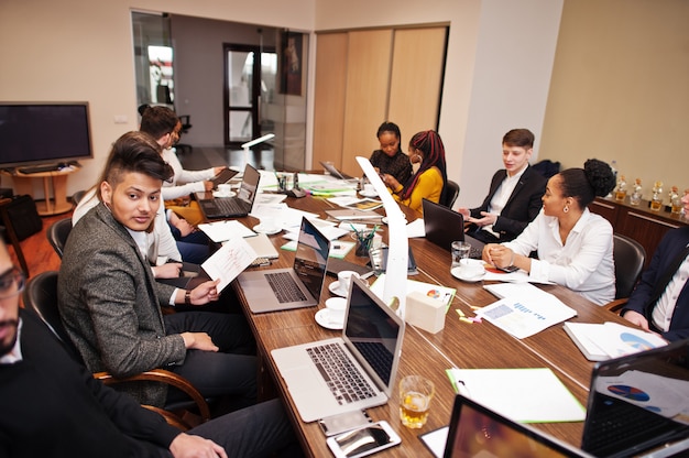 Equipo de negocios multirracial que aborda la reunión alrededor de la mesa de la sala de juntas.