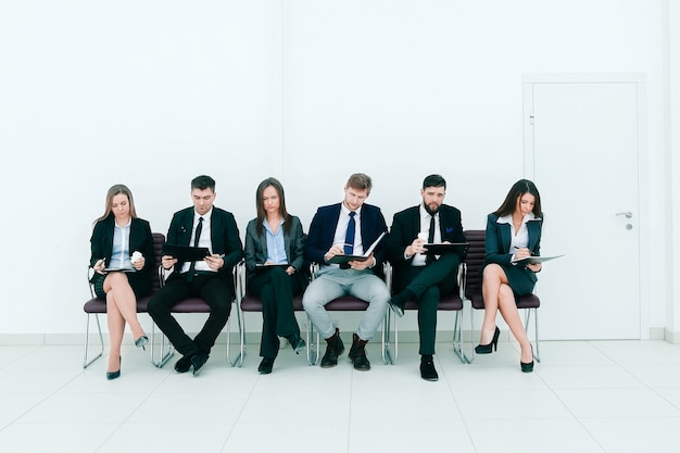 Equipo de negocios con portapapeles sentado en una fila.