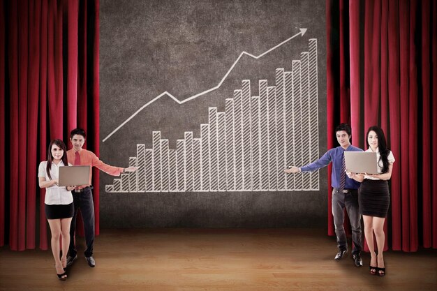 El equipo de negocios presenta el gráfico de barras de ganancias en el escenario