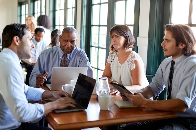 Equipo de negocios que tiene una reunión informal alrededor de una mesa en la cafetería