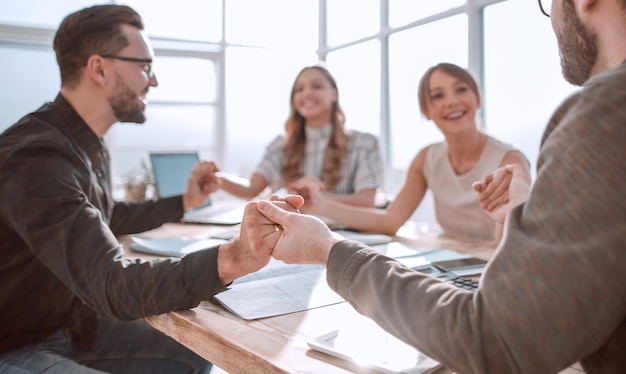 Equipo de negocios sentado a la mesa y mostrando su unidad.