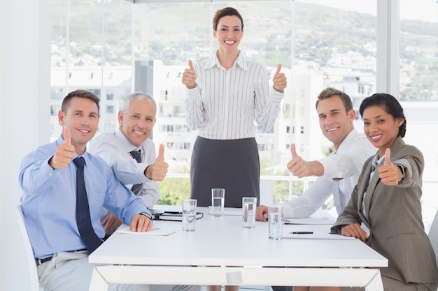 Equipo de negocios sonriendo a la cámara mostrando los pulgares para arriba