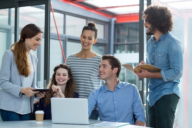 Equipo de negocios sonriente discutiendo sobre laptop en reunión