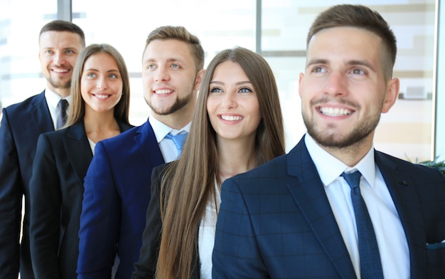 Equipo de negocios sonriente feliz de pie en una fila en la oficina