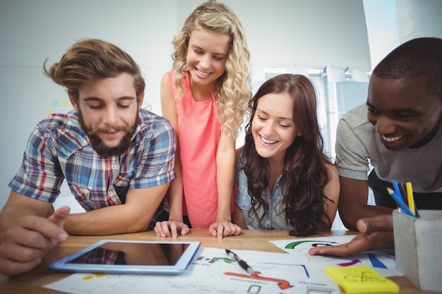 Equipo de negocios sonriente con tableta digital en el escritorio