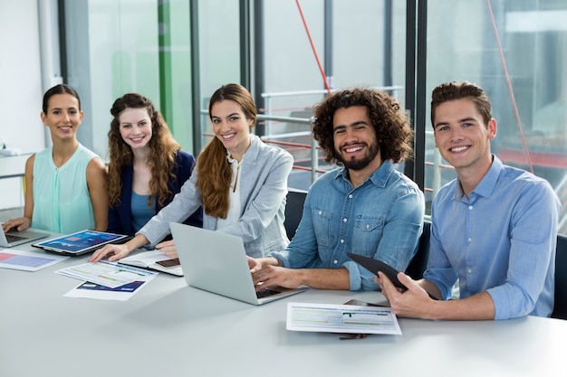 Equipo de negocios sonriente trabajando en computadora portátil y tableta digital en reunión