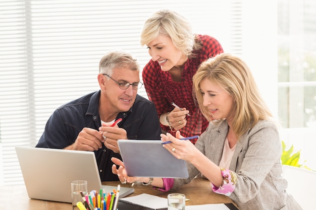 Equipo de negocios sonriente trabajando sobre una tableta