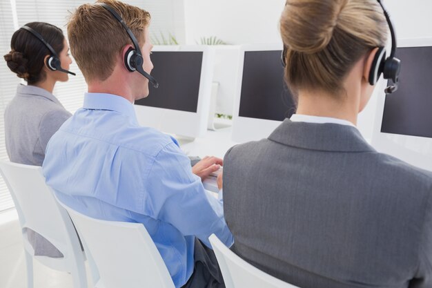 Equipo de negocios trabajando en computadoras y usando auriculares