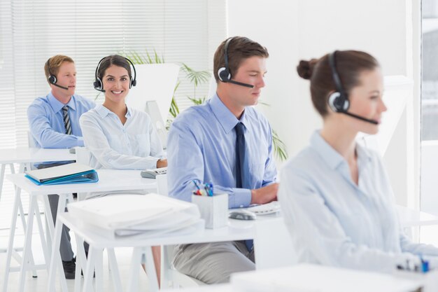 Equipo de negocios trabajando en computadoras y usando auriculares