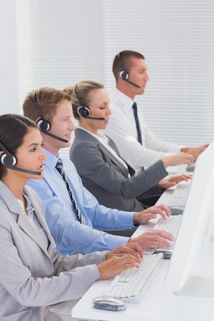 Equipo de negocios trabajando en computadoras y usando auriculares