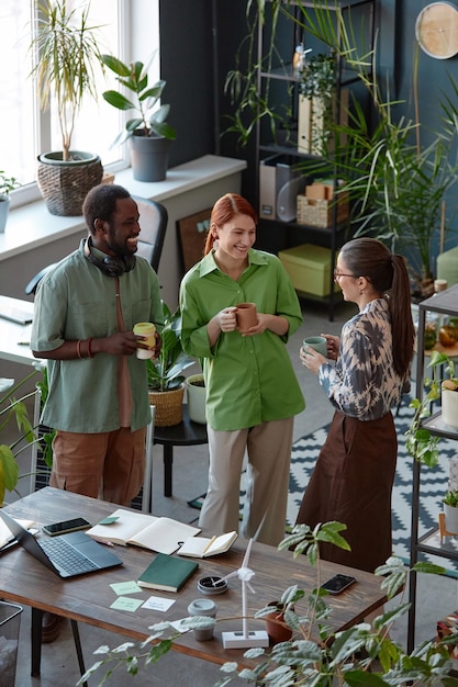 Un equipo de negocios de tres personas charlando en la pausa para el café.