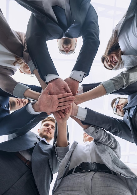 Equipo de negocios de vista inferior que muestra unidad con las manos juntas el concepto de trabajo en equipo