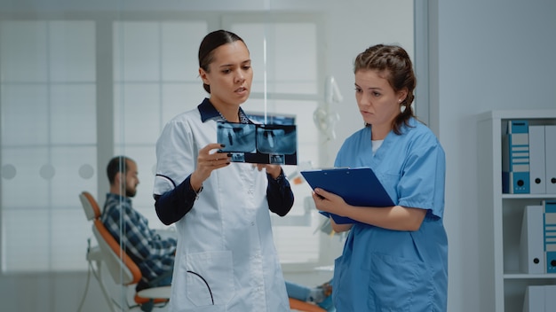 Equipo de odontología de ortodoncistas discutiendo el cuidado de los dientes del paciente