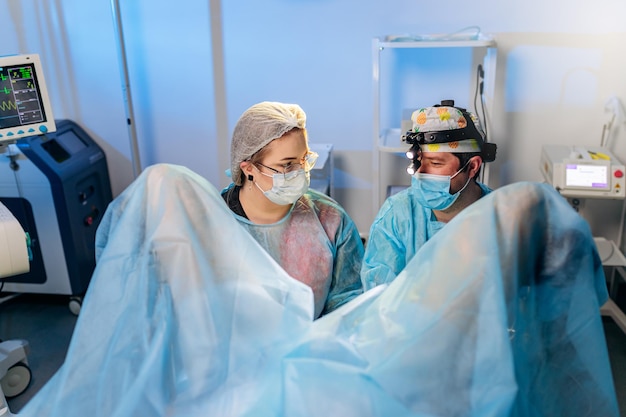 Equipo profesional de cirujanos proctólogos que realizan operaciones utilizando dispositivos médicos especiales en el quirófano del hospital Concepto quirúrgico urgente