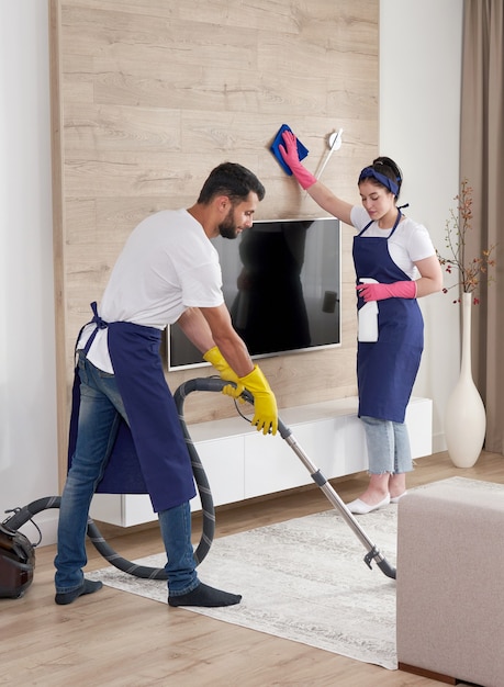Un equipo profesional de limpieza limpia la sala de estar en un apartamento moderno