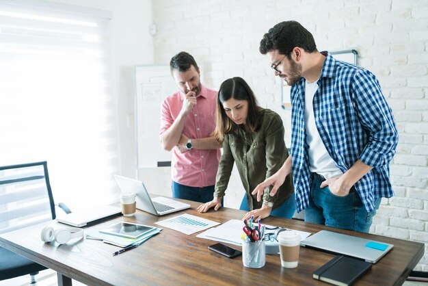 Equipo profesional revisando gráficos en la mesa de conferencias en la reunión de la junta en el espacio de coworking