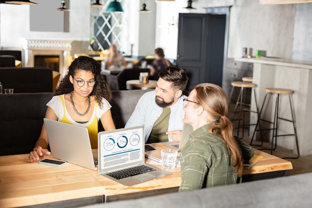 Equipo de profesionales. Gente agradable e inteligente que mira la pantalla del portátil mientras trabaja en equipo