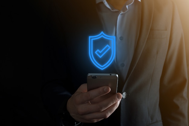 Equipo de seguridad de red de protección en manos de un empresario. concepto de negocio, tecnología, seguridad cibernética e internet - empresario presionando el botón escudo en pantallas virtuales Protección de datos.