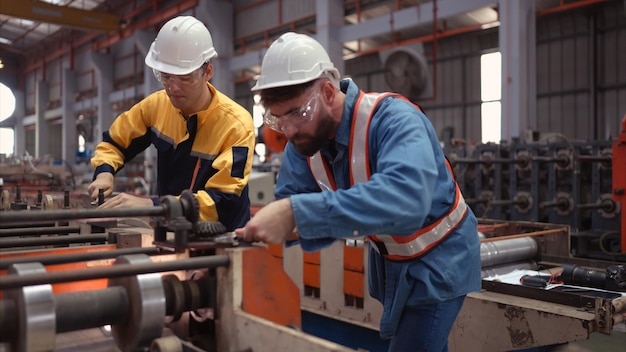 Un equipo de técnicos de la fábrica utiliza una llave inglesa para inspeccionar la cinta transportadora de la chapa metálica