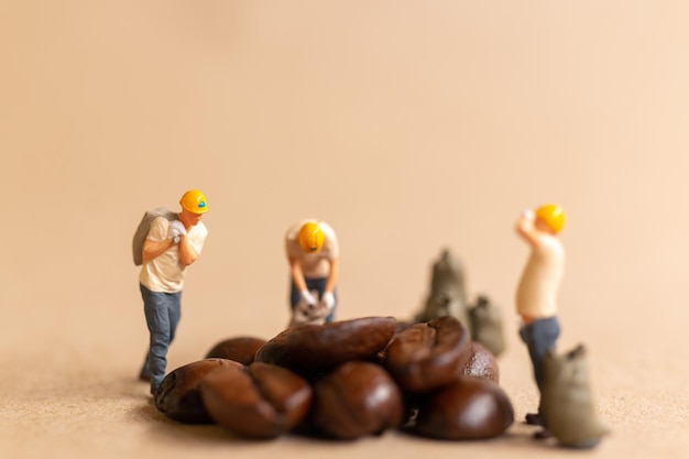 Equipo de trabajadores en miniatura trabajando con granos de café.