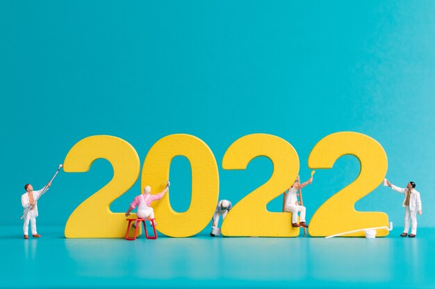 Equipo de trabajadores de personas en miniatura pintura número 2022, concepto de feliz año nuevo