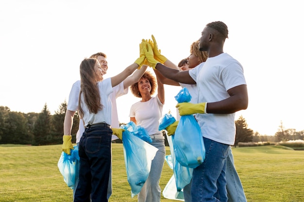 Foto equipo de voluntarios con guantes y con bolsas de basura se regocijan juntos en el éxito y los cinco altos