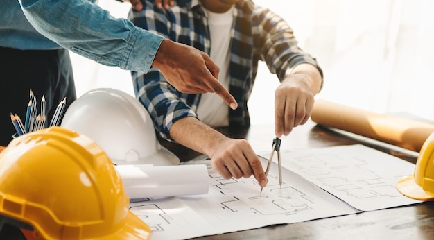Los equipos de ingenieros que se reúnen trabajando juntos usan cascos de trabajador en el sitio de construcción en la ciudad moderna Equipo profesional de la industria asiática en la oficina