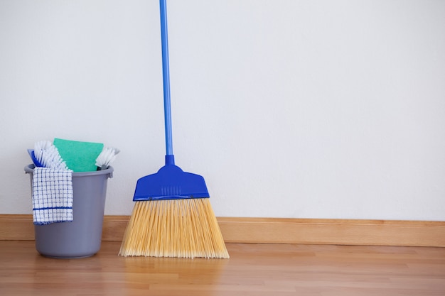 Equipos de limpieza en piso de madera contra pared