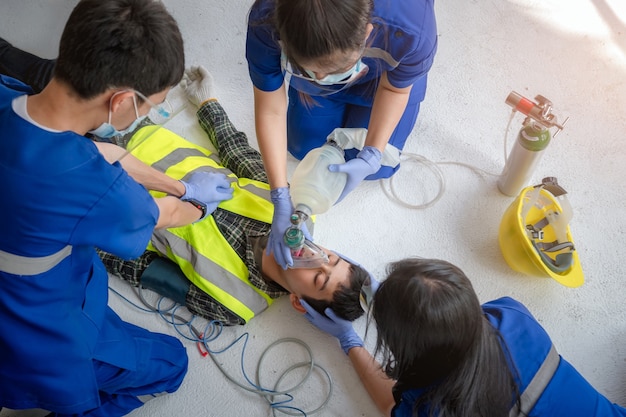 Los equipos médicos de emergencia ayudan a los pacientes inconscientes mediante el uso de desfibriladores externos automáticos (DEA) y el suministro de oxígeno. Durante el rescate de trabajadores inconscientes en el sitio de construcción.