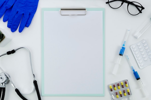 Foto equipos médicos con pastillas y papel en blanco en el portapapeles sobre fondo blanco